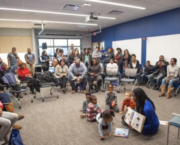 a crowd of adults sit around a children's read aloud at the cec in homewood