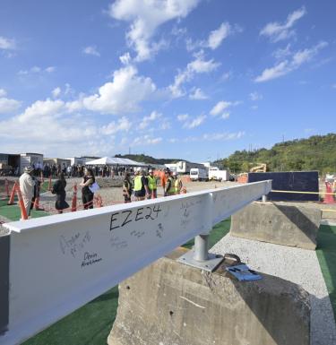 a white construction beam adorned with signatures that will be placed on the bioforge structure