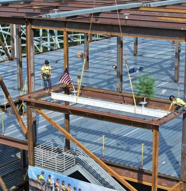 construction workers add a signed white beam to the bioforge structure